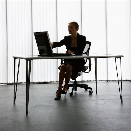 Silhouette of Caucasian businesswoman sitting at desk with computer working. Stock Photo - Budget Royalty-Free & Subscription, Code: 400-04006165