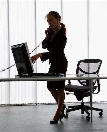 Silhouette of Caucasian businesswoman standing at computer  desk on telephone. Stock Photo - Budget Royalty-Free & Subscription, Code: 400-04006166