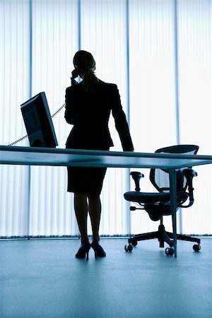 Silhouette of Caucasian businesswoman standing at computer desk on telephone. Stock Photo - Budget Royalty-Free & Subscription, Code: 400-04006170