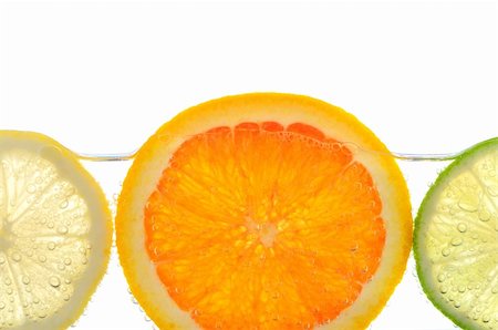 simsearch:632-06029470,k - Orange lemon and lime slices in water with air bubbles on white background Photographie de stock - Aubaine LD & Abonnement, Code: 400-04007221