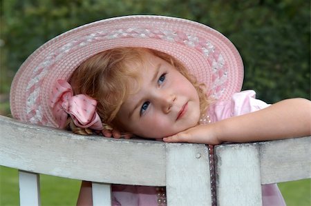Bonny lass leans her head on a wooden garden gate.  She is wearing a wide brimmed pink hat.  Gorgeous! Stock Photo - Budget Royalty-Free & Subscription, Code: 400-04007676