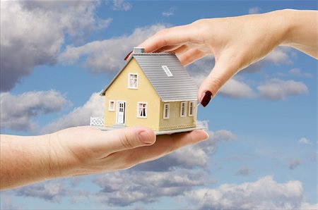 simsearch:400-07952800,k - Female hand reaching for a house on a partly cloudy sky background. Fotografie stock - Microstock e Abbonamento, Codice: 400-04009592