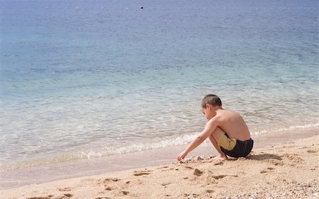 little boy playing with pebbles on a clean empty beach Stock Photo - Budget Royalty-Free & Subscription, Code: 400-04009934