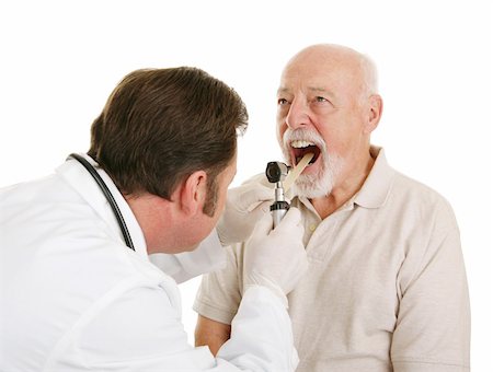 doctor elderly patient - Doctor using a tongue depressor and an otoscope to look inside a senior patient's mouth.  Isolated on white. Foto de stock - Super Valor sin royalties y Suscripción, Código: 400-04000467