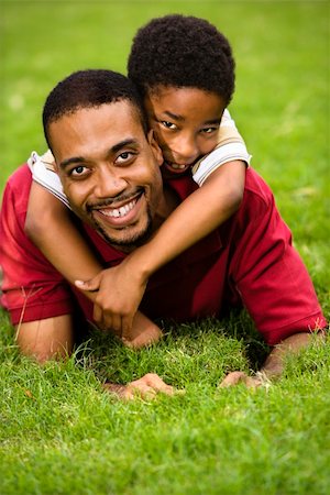 Father lying in grass smiling as son climbs on his back and hugs his neck. Photographie de stock - Aubaine LD & Abonnement, Code: 400-04002865