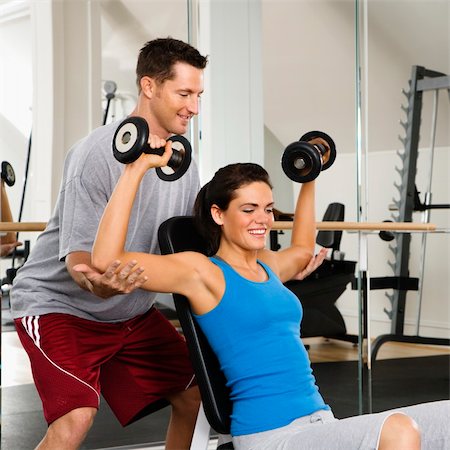 spotting at the gym - Man assisting woman at gym with hand weights smiling. Stock Photo - Budget Royalty-Free & Subscription, Code: 400-04002889