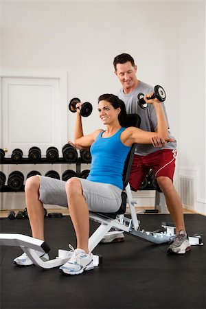spotting at the gym - Man assisting woman at gym with hand weights smiling. Stock Photo - Budget Royalty-Free & Subscription, Code: 400-04002891