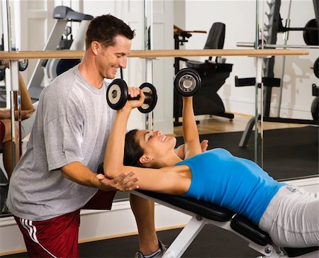 posição - Man assisting woman at gym with hand weights smiling. Foto de stock - Royalty-Free Super Valor e Assinatura, Número: 400-04002892