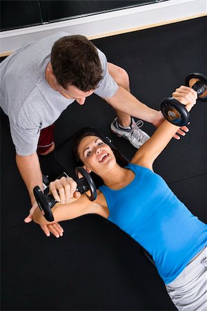 posição - Man assisting woman lifting weights at gym. Foto de stock - Royalty-Free Super Valor e Assinatura, Número: 400-04002905