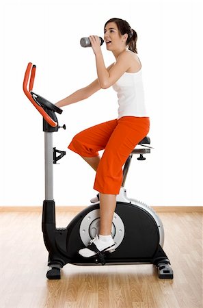 simsearch:400-04027186,k - Young woman training on exercise bike at the gym and drinking water Stockbilder - Microstock & Abonnement, Bildnummer: 400-04003190
