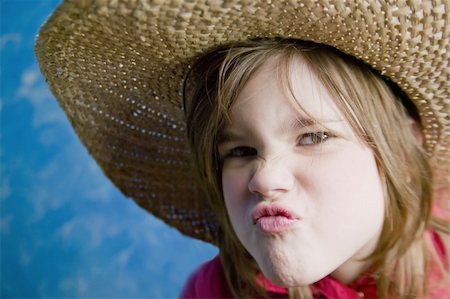 Little girl wearing a straw cowboy hat makes a funny face Fotografie stock - Microstock e Abbonamento, Codice: 400-04015731