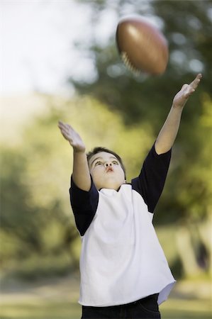 pigskin - Young boy with arms stretched out to catch a football Photographie de stock - Aubaine LD & Abonnement, Code: 400-04015903