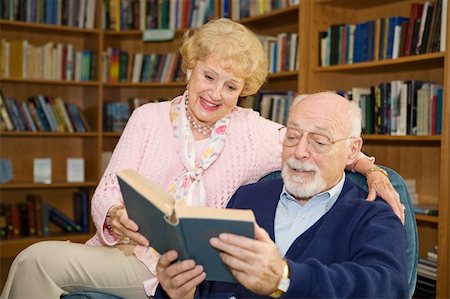 simsearch:400-04109826,k - Senior couple enjoying a good book together in the library. Fotografie stock - Microstock e Abbonamento, Codice: 400-04015986