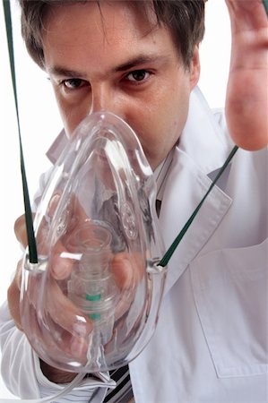 A doctor leaning over a patient to stretching the elastic to place an oxygen mask on their face.  Could also be anesthesia or laughing gas.   From patient perspective. Stock Photo - Budget Royalty-Free & Subscription, Code: 400-04017265