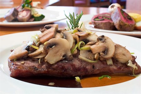 simsearch:400-04440947,k - Juicy platter of beef steak topped with warm mushrooms. Served with mashed potatoes, carrots, beans, zucchini and an assortment of sauces. Fotografie stock - Microstock e Abbonamento, Codice: 400-04017272