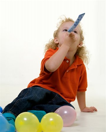 Adorable little three year old boy wearing party hat sitting with balloons blowing on a party favor Stock Photo - Budget Royalty-Free & Subscription, Code: 400-04017830