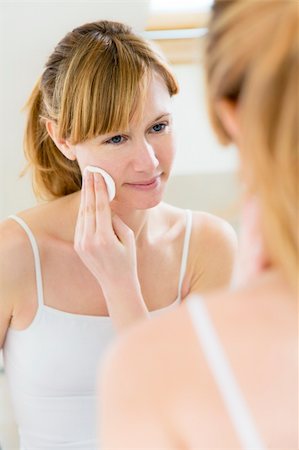 young woman using a cotton pad to remove her make-up Stockbilder - Microstock & Abonnement, Bildnummer: 400-04019483