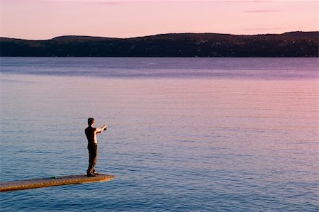 A young man fishing in the ocean at sunset Stock Photo - Budget Royalty-Free & Subscription, Code: 400-04011831