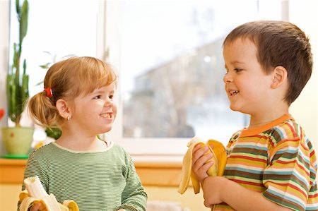 Happy little girl and boy eating bananas Stock Photo - Budget Royalty-Free & Subscription, Code: 400-04013558
