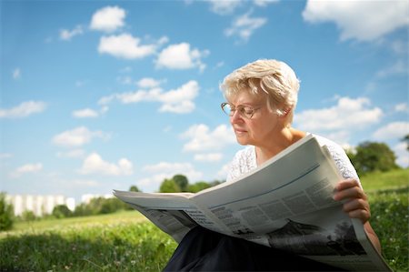 simsearch:693-06019332,k - The woman in old age sits on a grass in park on a background of the blue sky and reads the newspaper Stock Photo - Budget Royalty-Free & Subscription, Code: 400-04026005
