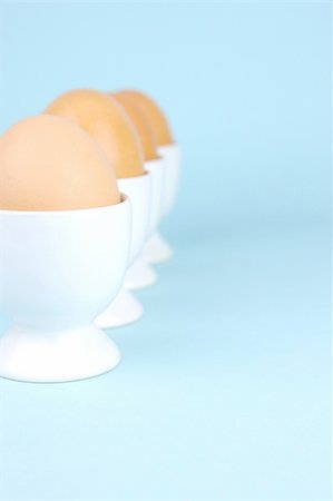 Hard boiled eggs and egg cups isolated against a blue background Stock Photo - Budget Royalty-Free & Subscription, Code: 400-04026028