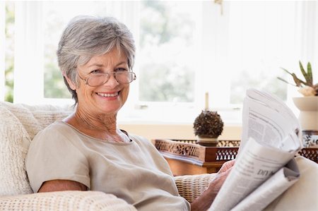 simsearch:400-04026722,k - Woman in living room reading newspaper smiling Stock Photo - Budget Royalty-Free & Subscription, Code: 400-04026725