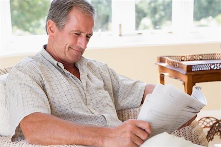 Man in living room reading newspaper smiling Stock Photo - Budget Royalty-Free & Subscription, Code: 400-04026735