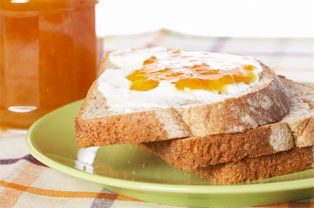 spreading butter on bread - Toast with butter and peach jam glass jar in the green plate with soft shadow on square mat background. Shallow depth of field Stock Photo - Budget Royalty-Free & Subscription, Code: 400-04028391