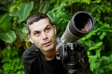 person focusing telescope - Handsome nature guide with a telescope in the rainforest Stock Photo - Budget Royalty-Free & Subscription, Code: 400-04023830