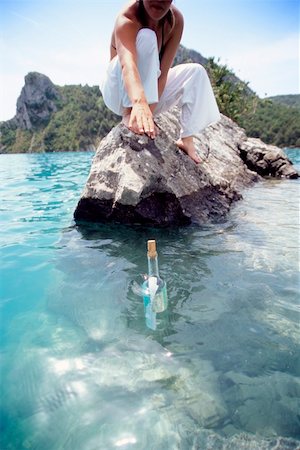 Young woman reaching for a message in a bottle Foto de stock - Royalty-Free Super Valor e Assinatura, Número: 400-04034974