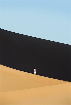 simsearch:400-04034980,k - Woman walking across desert sand dunes Foto de stock - Royalty-Free Super Valor e Assinatura, Número: 400-04034978