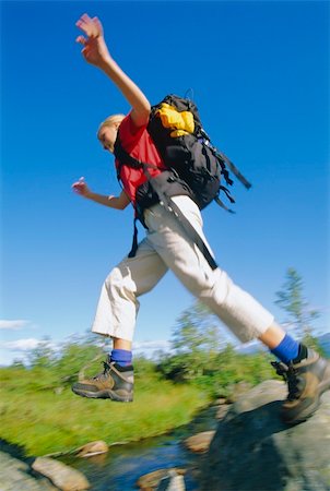 Young woman wearing backpack leaping across river Stock Photo - Budget Royalty-Free & Subscription, Code: 400-04034987