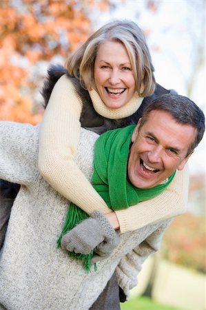 Senior man giving woman piggyback ride through autumn woods Stock Photo - Budget Royalty-Free & Subscription, Code: 400-04035087