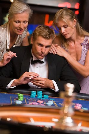 Man gambling at casino surrounded by glamorous women at roulette table Stock Photo - Budget Royalty-Free & Subscription, Code: 400-04035678