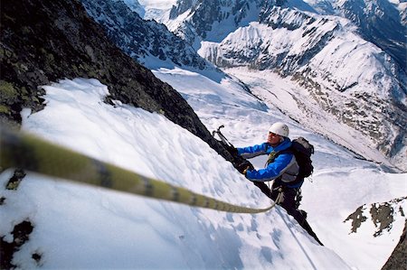 simsearch:400-04036380,k - Young men mountain climbing on snowy peak Photographie de stock - Aubaine LD & Abonnement, Code: 400-04036392