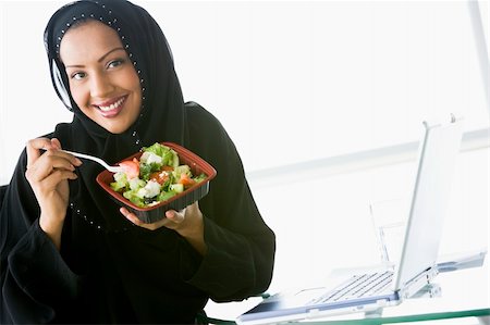 A Middle Eastern businesswoman eating salad beside her laptop Stock Photo - Budget Royalty-Free & Subscription, Code: 400-04037038