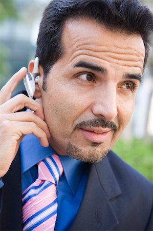 Businessman using bluetooth earpiece outside Stock Photo - Budget Royalty-Free & Subscription, Code: 400-04037100