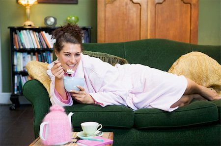 A young woman lying on her couch eating cereal Stock Photo - Budget Royalty-Free & Subscription, Code: 400-04037406