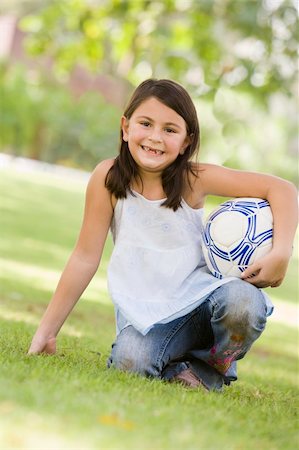 Girl in park holding football looking to  camera Foto de stock - Super Valor sin royalties y Suscripción, Código: 400-04038300