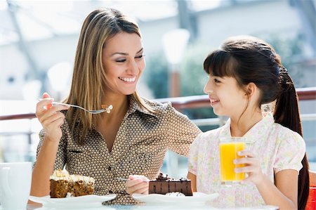 Mother and daughter eating cake and drinking juice in cafe Stock Photo - Budget Royalty-Free & Subscription, Code: 400-04038352