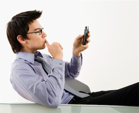 simsearch:400-04639378,k - Asian businessman sitting at desk texting using his pda cellphone. Stock Photo - Budget Royalty-Free & Subscription, Code: 400-04039910