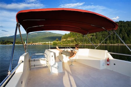 A young male driving a house boat from the upper helm. Stock Photo - Budget Royalty-Free & Subscription, Code: 400-04031527