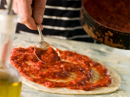 simsearch:400-04031652,k - Man Spooning Tomato sauce onto a Pizza Base Stock Photo - Budget Royalty-Free & Subscription, Code: 400-04031548