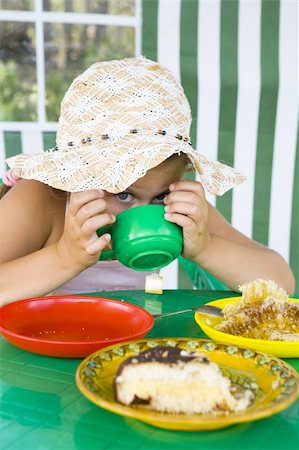 Little girl in big hat eats sweets and drinks tea Stock Photo - Budget Royalty-Free & Subscription, Code: 400-04033066