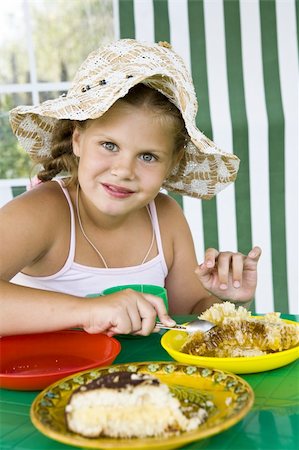 Little girl in big hat eats sweets and drinks tea Stock Photo - Budget Royalty-Free & Subscription, Code: 400-04033069