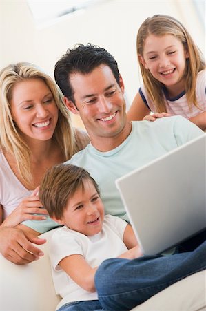 simsearch:400-04044134,k - Family in living room with laptop smiling Fotografie stock - Microstock e Abbonamento, Codice: 400-04044079