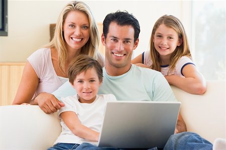 simsearch:400-04044134,k - Family in living room with laptop smiling Fotografie stock - Microstock e Abbonamento, Codice: 400-04044081