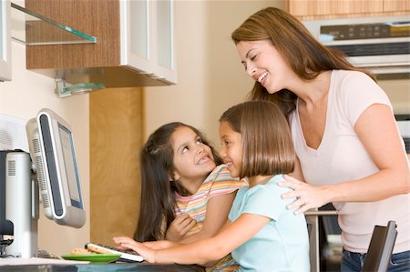 simsearch:400-04044134,k - Woman and two young girls in kitchen with computer smiling Fotografie stock - Microstock e Abbonamento, Codice: 400-04044105