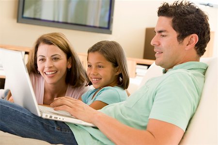 Family in living room with laptop smiling Foto de stock - Super Valor sin royalties y Suscripción, Código: 400-04044109