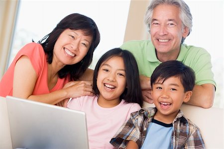 simsearch:400-04044134,k - Couple with two young children in living room with laptop smilin Fotografie stock - Microstock e Abbonamento, Codice: 400-04044102